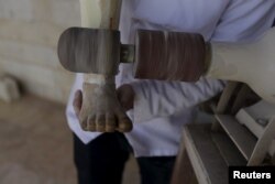 Khamis, 24, files an artificial limb inside a workshop in the rebel-controlled area of Maaret al-Numan town in Idlib province, Syria, March 20, 2016.