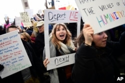 Madison Gray, a Temple University student, holds up her sign during a protest against President Donald Trump's executive order banning travel to the U.S. by citizens of Iraq, Syria, Iran, Sudan, Libya, Somalia or Yemen, Sunday, Jan. 29, 2017, at Philadelphia International Airport in Philadelphia.