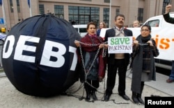 FILE - Protesters asking to drop the Pakistan's debt stand a "Friends of Democratic Pakistan" meeting in Brussels, Belgium.