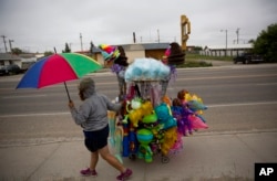 A vendor wheels her cart of souvenirs before the start of the North American Indian Days parade on the Blackfeet Indian Reservation in Browning, Mont., Saturday, July 14, 2018