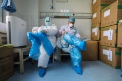 湖北武汉红十字会医院的医护人员在进入新冠病毒隔离病房前在穿戴防护用品。（2020年2月24日）