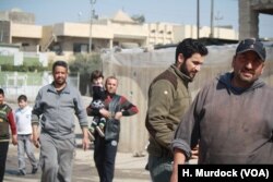 Mahmoud Abd (R) and his neighbors say they continue to be sickened by the smell from a nearby suspected chemical bomb and they still don't know exactly what was in it, in eastern Mosul, Iraq, March 8, 2017.