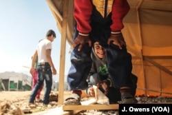 A young Syrian boy helps out his family's efforts to rebuild a shelter in the camp they have just moved to.