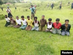 FILE - Ten Rohingya Muslim men with their hands bound kneel as members of the Myanmar security forces stand guard in Inn Din village, Sept. 2, 2017.