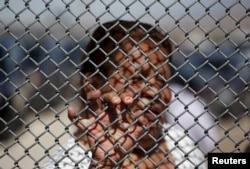 FILE - A Mexican migrant talks to a family member through the border fence between Ciudad Juarez and El Paso, United States, after a bi-national Mass in support of migrants in Ciudad Juarez, Mexico, Feb.15, 2016.