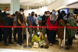 Seorang perempuan duduk di lantai saat dia mengantre untuk menerima dosis vaksin Sinovac China di sebuah pusat perbelanjaan di Jakarta, 1 April 2021. (Foto: REUTERS /Ajeng Dinar Ulfiana)