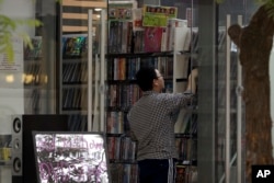 FILE - A man shops at a store selling DVDs and CDs in Beijing, April 27, 2016. China has been one of several countries targeted by U.S. officials for leaving American producers of music, movies and other copyrighted material open to rampant piracy.