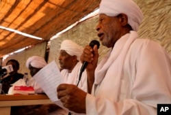 FILE - Ibrahim al-Senoussi, a former aide to ousted President Omar al-Bashir, right, speaks at a press conference a day after a meeting of the Popular Congress Party, an Islamist party close to al-Bashir, was attacked by protesters, in Khartoum, Sudan.