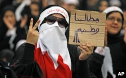 FILE -A Bahraini female Shi'ite protester holds a sign reading: "our demands are for country" during a rally in the village of Diraz, West of Manama, July 1, 2011