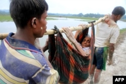 Pengungsi Rohingya membawa seorang perempuan tua dari Rakhine di Myanmar dekat Teknaf di Bangladesh, 3 September 2017.