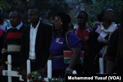 Mourners, some wearing national colors, carry white crosses — 148 of them, symbolizing those killed in the Garissa University College attack last week in Kenya.