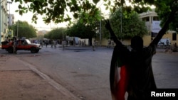 A Sudanese protester chants slogans as security forces prepare to disperse them along a street during demonstrations in central Khartoum, Sudan, May 15, 2019.