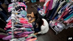 Immigrants seeking asylum, Natalia Oliveira da Silva and her daughter, Sara, 5, look through donated clothing at a Catholic Charities facility, July 23, 2018, in San Antonio, Texas.