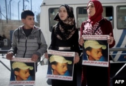 Relatives of Palestinian teenager Mohammed Abu Khdeir who was killed in 2014, hold posters bearing his portrait outside the Jerusalem district court during a hearing on Feb. 4, 2016.