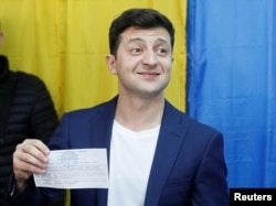 Ukrainian presidential candidate Volodymyr Zelenskiy holds up his ballot while standing in front of the media at a polling station during the second round of a presidential election in Kyiv, Ukraine, April 21, 2019.