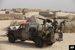 FILE - UN peacekeepers from Burkina Faso stand guard during a patrol through a neighborhood on the outskirts of Timbuktu, Mali, March 31, 2014.