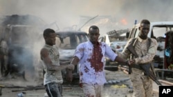 A Somali soldier helps a civilian who was wounded in a blast in the capital of Mogadishu, Somalia, Saturday, Oct. 14, 2017.