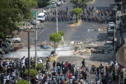 Perwira militer turun tangan selama protes terhadap kudeta militer di Yangon, Myanmar, 2 Maret 2021. Gambar diambil dari balik jendela. (Foto: Reuters)