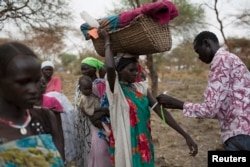 A mother carrying her baby in a basket is screened for malnutrition at a joint UNICEF-World Food Program Rapid Response Mission, which delivers critical supplies and services to those displaced by conflict, in Nyanapol, South Sudan, March 3, 2015.