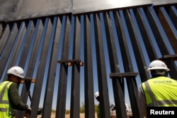 FILE - Construction workers check a new section of bollard wall in Santa Teresa, N.M., as seen from the Mexican side of the border in San Jeronimo, on the outskirts of Ciudad Juarez, Mexico,
