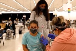 Anaiya Layland (12) menerima dosis pertama vaksin COVID-19 Pfizer, ditemani ibunya, Ashlesha Patel, di Departemen Kesehatan Masyarakat Cook County, di Des Plaines, Ill, Kamis, 13 Mei 2021. (AP Photo / Shafkat Anowar)