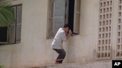 FILE PHOTO - A Cambodian student tries to throw the form of hand-delivered crib notes to help his friends while they are examining inside the Phnom Penh's school on Wed. July 3, 1996.