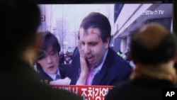 South Korean men watch a TV news program reporting U.S. Ambassador to South Korea Mark Lippert injured in a knife attack at Seoul railway station in Seoul, South Korea, Thursday, March 5, 2015. Lippert was slashed on the face and wrist by a man wielding a