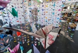 Origami berbentuk burung bangau, yang dibuat dari lembaran bergambar komik pada koran bekas, digantung bersama ribuan origami lainnya untuk mengenang korban Covid-19 di Matter Studio Gallery, Los Angeles, Selasa, 11 Agustus 2020.