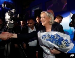 French far-right leader Marine Le Pen celebrates with supporters while holding a bouquet of flowers at her election day headquarters in Henin-Beaumont, northern France, April 23, 2017.