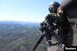 A soldier flies in a helicopter as he patrols at a poppy plantation used to make heroin during a military operation in the state of Sinaloa, Mexico, March 18, 2017.