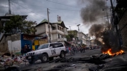 A United Nations vehicle drives past a barricade of burning tires during a demonstration against high prices and fuel shortages in Port-au-Prince, on Oct. 21, 2021.