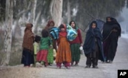 Displaced flood victims in Pakistan carry donated items by passing vehicles ahead of the winter weather.