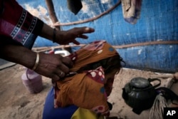 Hagar Yahia pulls the veil off of her malnourished 5-year-old daughter, Awsaf, to feed her, in their hut in Abyan, Yemen, in this Feb. 15, 2018 photo.