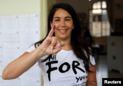 A woman shows her ink-stained finger after casting her vote during the parliamentary election in Beirut, Lebanon, May 6, 2018.