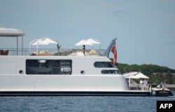FILE - Former U.S. President Obama take a holiday photo of his wife Michelle, as she poses on the top deck of the 138-meter Rising Sun yacht where the couple and friends spent the morning off the Island of Moorea, in the South Pacific.