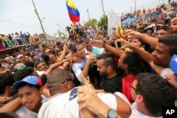 Juan Guaidó, opposition leader and self-proclaimed interim president of Venezuela, is surrounded by supporters at the end of a rally on the shore of Lake Maracaibo in Cabimas, Venezuela, April 14, 2019.