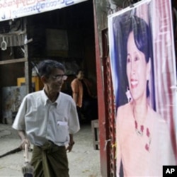 A member of Burna's detained opposition leader Aung San Suu Kyi's National League for Democracy party walks past her portrait outside the party's headquarters, Rangoon.