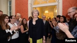 Staff members applaud as Britain's new Prime Minister Theresa May walks into 10 Downing Street after May met Queen Elizabeth in Buckingham Palace, in central London, Britain, July 13, 2016.