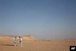In this Feb. 7, 2018, photo, two scientists test space suits and a geo-radar for use in a future Mars mission in the Dhofar desert of southern Oman.