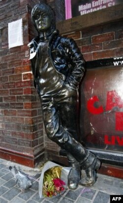 Catatan dan bung diletakan di patung John Lennon di luar Cavern Pub di Mathew Street, Liverpool, Inggris, 8 Desember 2010.