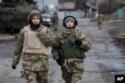 FILE - Ukrainian government army women soldiers patrol an area in the village of Debaltseve, Donetsk region, eastern Ukraine, Dec 24, 2014.