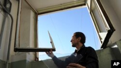 Warga Rusia memperbaiki kaca jendela yang pecah akibat goncangan yang ditimbulkan oleh jatuhnya meteor di Chelyabinsk, Rusia (15/2).