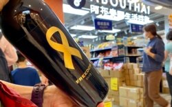 香港市民丁小姐在沙田一间阿布泰分店排队约40分钟，购买阿布泰独家发售，2019年酿制、贴上象征自由的黄丝带及香港加油标贴的红酒 (美国之音/汤惠芸)
