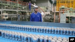 FILE - Asahi Breweries plant manager Shinichi Uno watches the production line at an Asahi Breweries factory in Moriya near Tokyo, May 29, 2017.