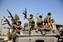 FILE - Shi'ite fighters, known as Houthis, ride on a patrol truck as they chant slogans during a tribal gathering showing support for the Houthi movement in Sanaa.