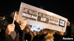 People hold a placard which reads "I am Muslim, I am Jewish, I am Catholic, I am Charlie" at a vigil, following the shooting at the satirical newspaper Charlie Hebdo, Jan. 8, 2015.