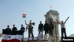 Soldiers loyal to the regime and civilians holding the Syrian national flag stand near boxes containing aid from the Syrian army in Qusair, June 5, 2013.
