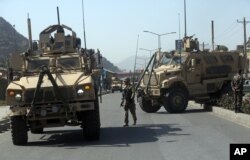 FILE - A U.S. soldier directs his colleagues at the site a bomb attack that targeted several armored vehicles belonging to forces attached to the NATO Resolute Support Mission, in downtown of Kabul.
