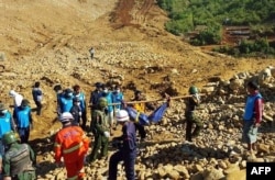FILE - Soldiers carry the bodies of miners killed by a landslide in a jade mining area in Hpakhant, in Myanmar's Kachin state. Nov. 22, 2015.