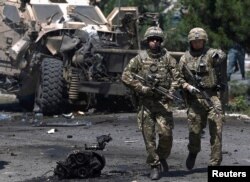 FILE - NATO soldiers walk at the site of a suicide bomb attack in Kabul, Afghanistan, June 30, 2015.